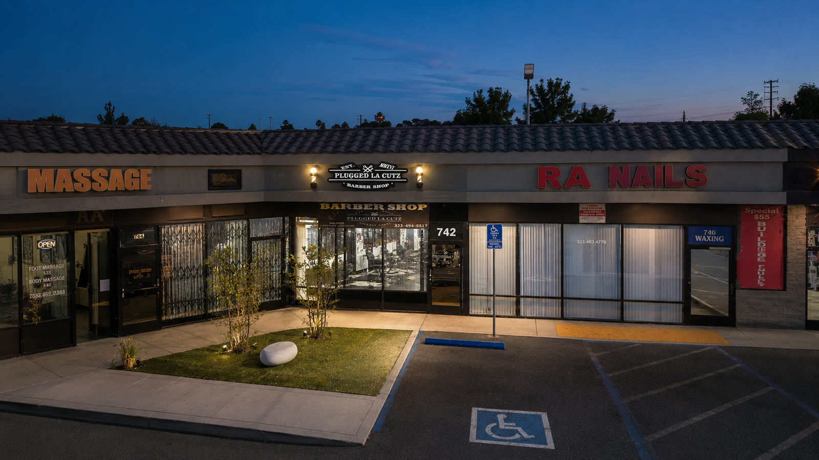 The lit Plugged LA Cutz storefront seen from above at dusk.