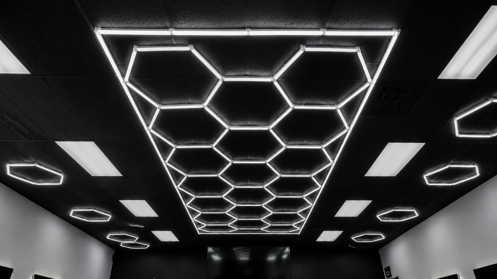 Looking up at the honeycomb of cool-white hexagonal LED lights set into the black ceiling.